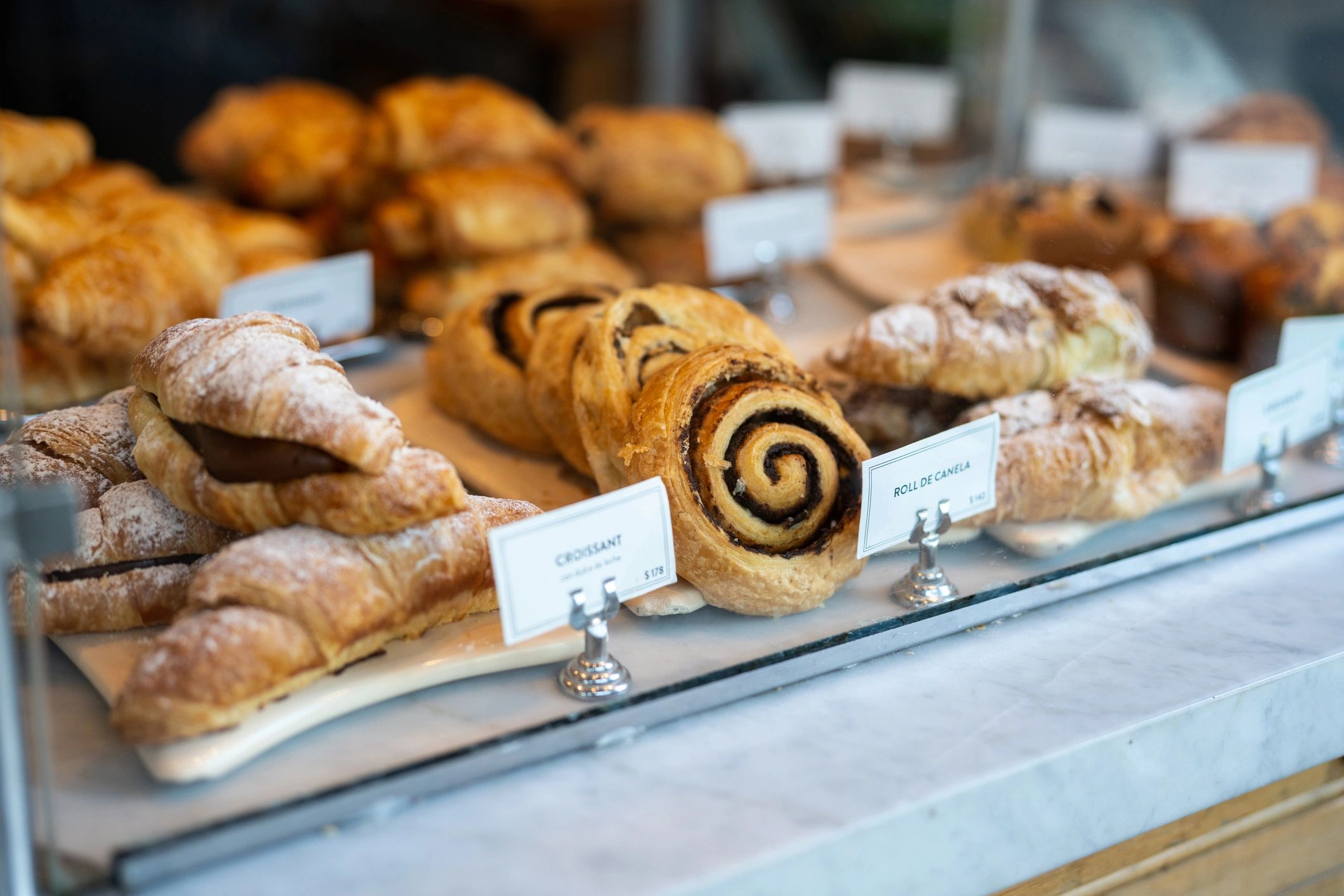 Assorted pastries displayed on trays in a bakery case.