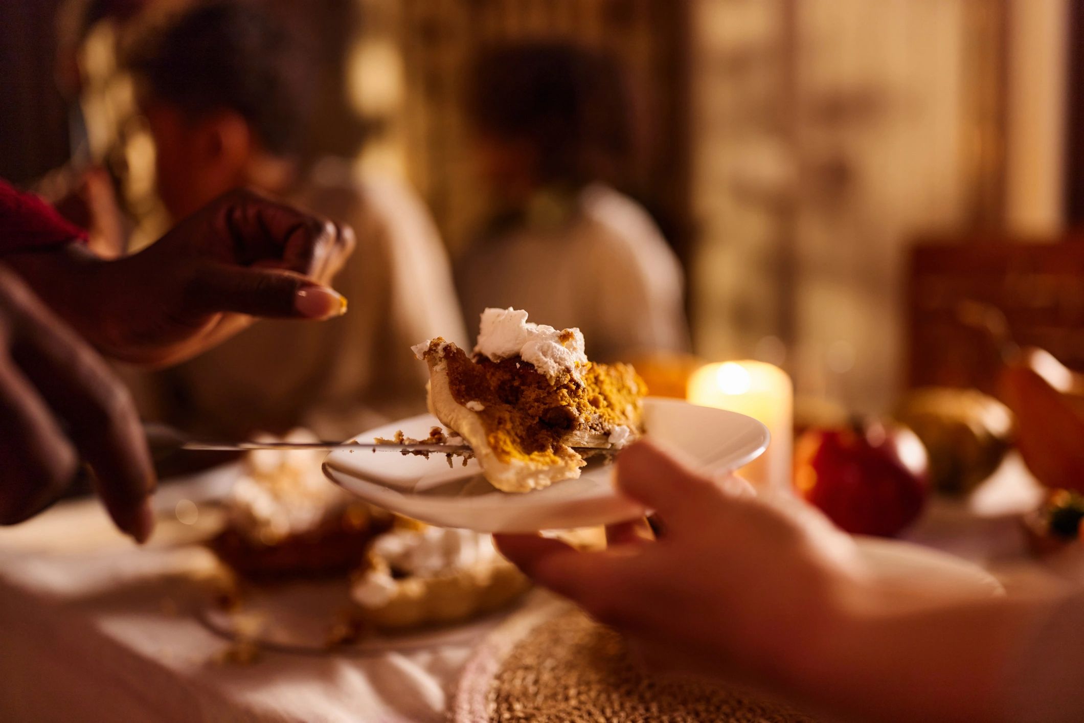 Hands holding a slice of cake on a plate
