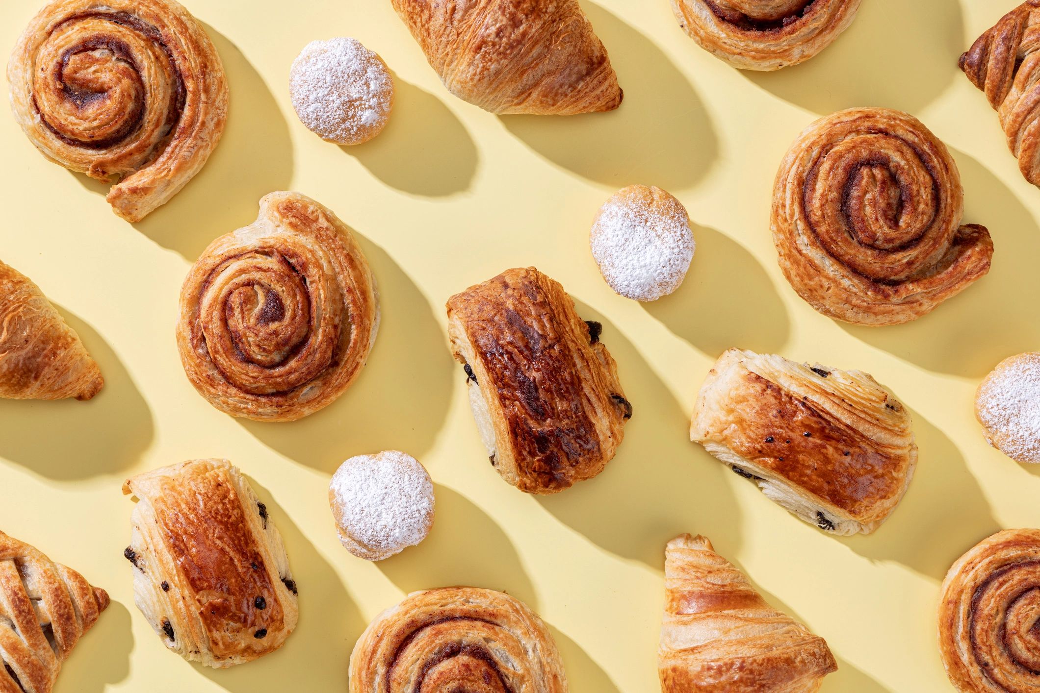 Assorted freshly baked pastries on a light yellow background